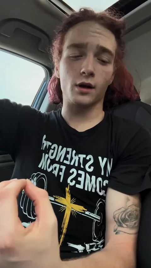 Nathan Johnson in his car, wearing a T-shirt that reads "My strength comes from the Lord"